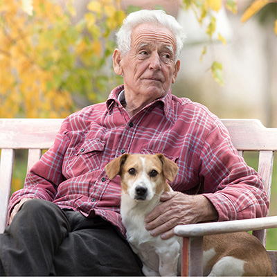 elderly male resident sitting on an outdoor bench with a dog