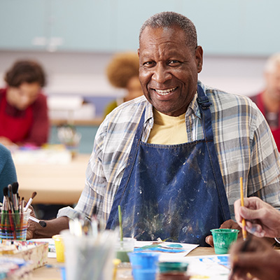 elderly resident smiling while painting at a craft table