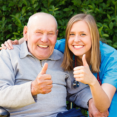 smiling resident and caregiver holding a thumbs up