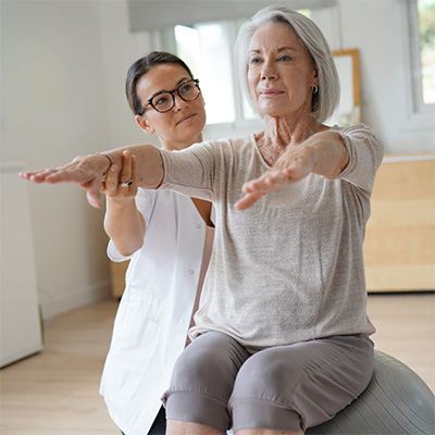 rehab nurse assisting elderly female resident with arm exercise