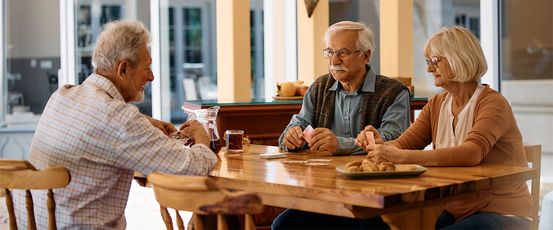 3 people seated at a wooden table with drinks and paperwork